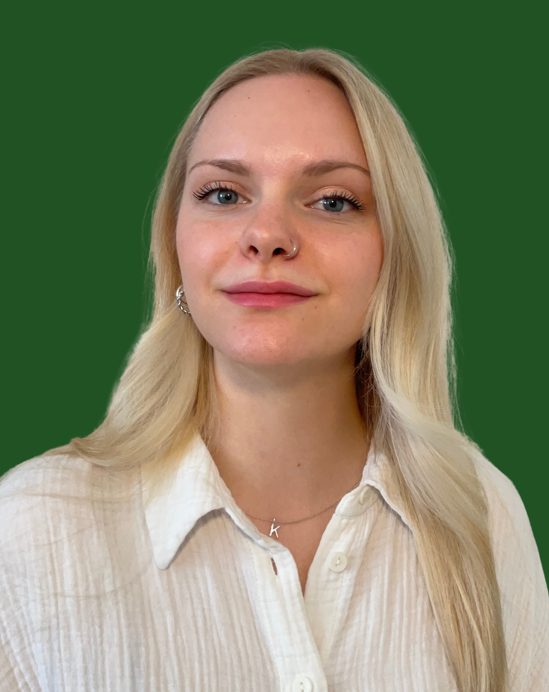 Portraitbild von Kristin Mellon in einer weißen Bluse vor einem grünen Hintergrund.